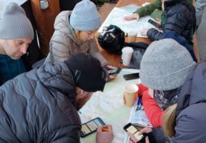 a group of students on an avalanche course plan out their trip around a table using a topographic map
