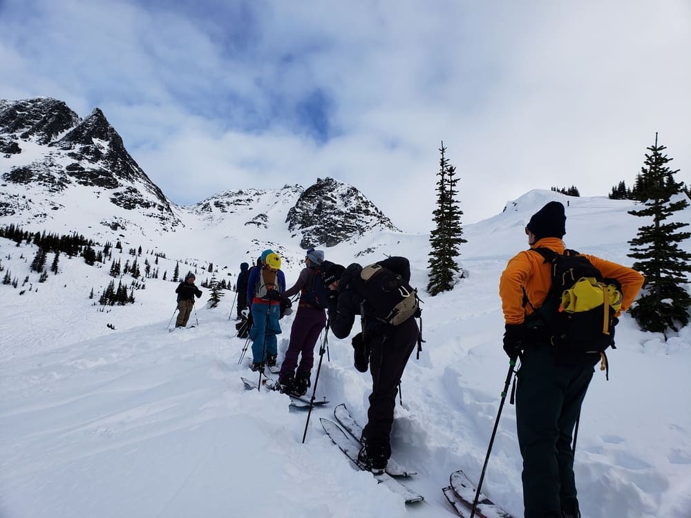 a group of students climb a mountain for an AST avalanche course