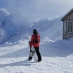 a snowboarder stands on top of chair 8 at mount baker ski area, looking at mount shuksan