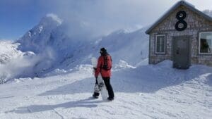 a snowboarder stands on top of chair 8 at mount baker ski area, looking at mount shuksan