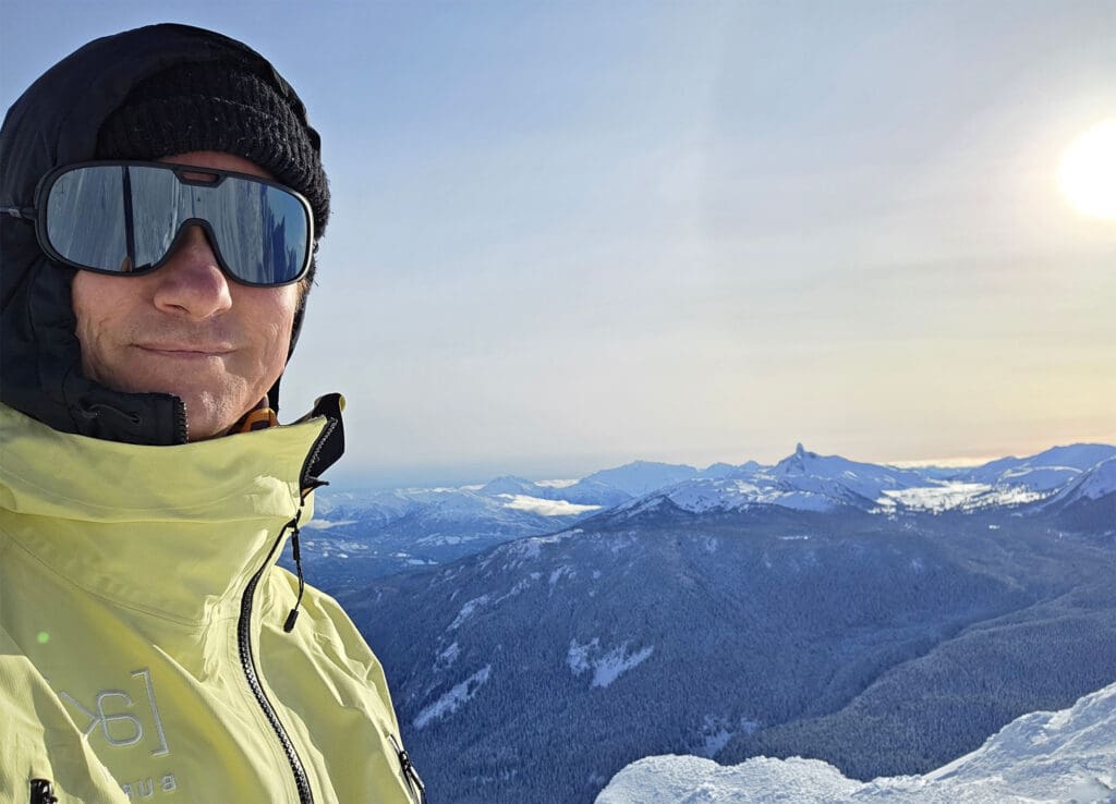 a splitboarder poses for a photo with black tusk and garibaldi park in the background