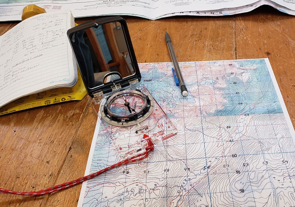 a topographic map and compass being used to plan out a trip on a dining table