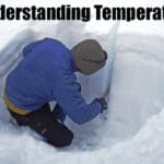 a man looks into a snow pit to determine the safety of the snowpack