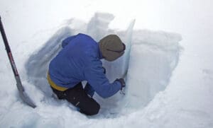 an avalanche professional digging a snow pit