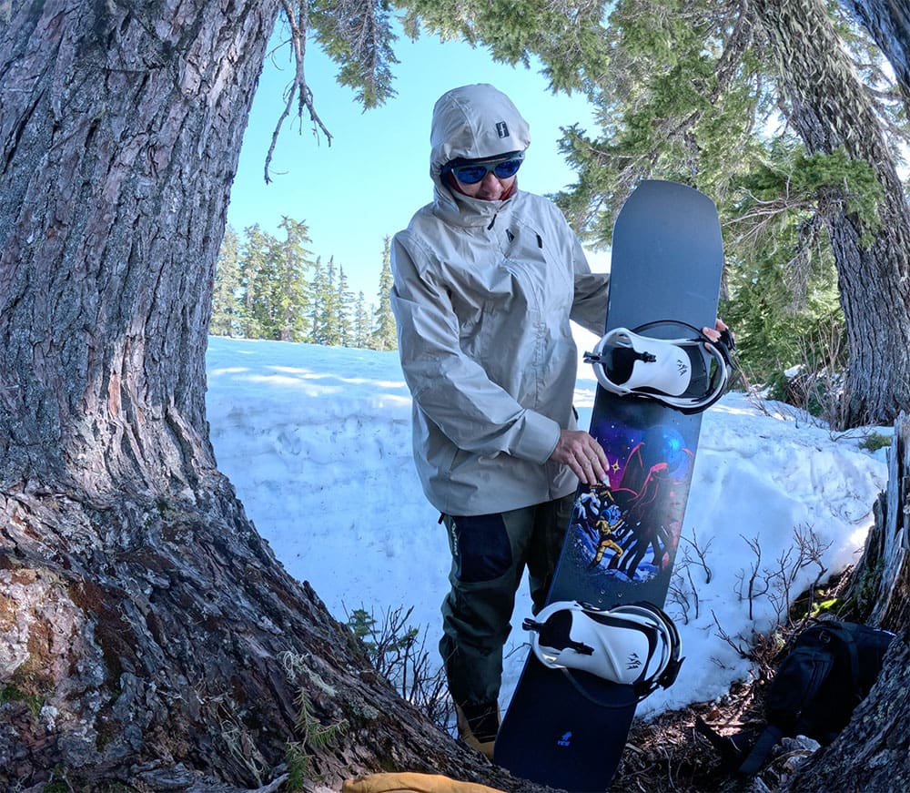 a snowboarder holding up the YES. Sender XTRM snowboard during a review