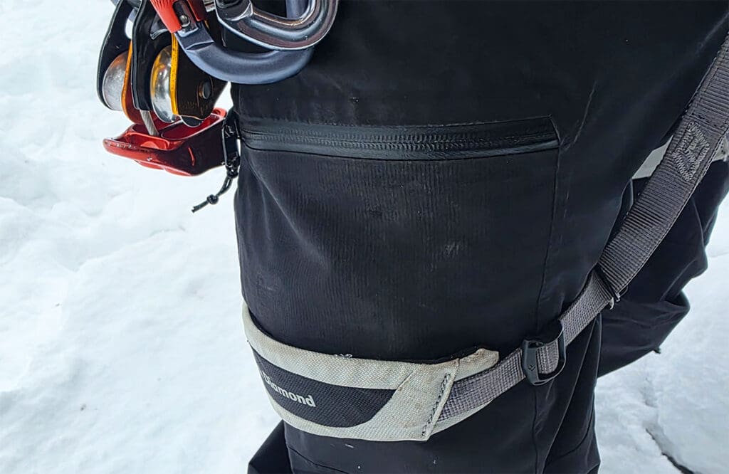 A view of the thigh pocket on the jones mtn surf snowboard pant with a climbing harness