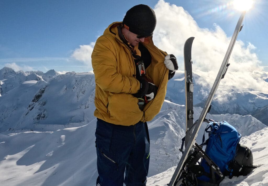 looking inside the jacket pocket of a backcountry skier high in the alpine mountains mid transition
