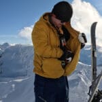 a backcountry snowboarder puts skins on the inside of his puffy midlayer jacket