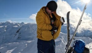 a backcountry snowboarder puts skins on the inside of his puffy midlayer jacket