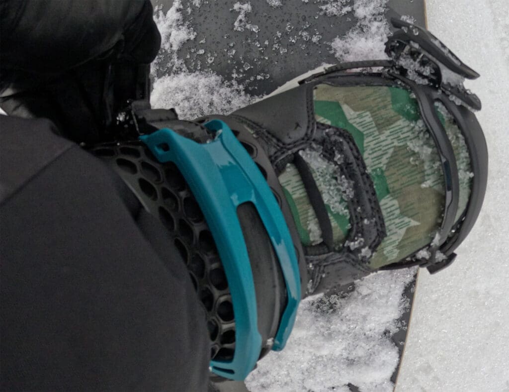 a snowboarder tightens the ankle strap on his snowboard bindings