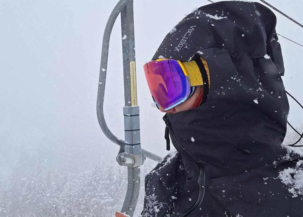 a close up of a snowboarder on the chairlift and the hood cinch on his jacket