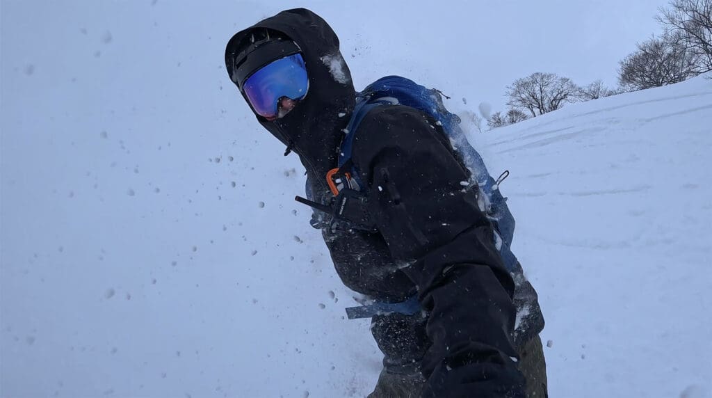 a snowboarder emerges from a cloud of powder