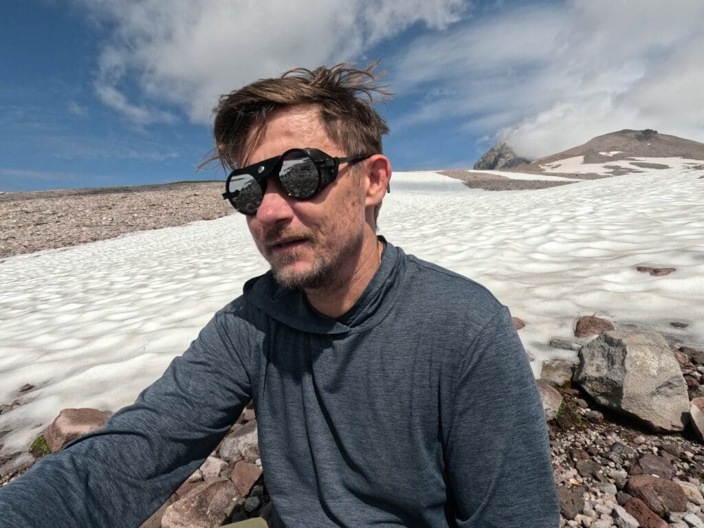 a man high up on a mountain next to a snowfield in garibaldi provincial park