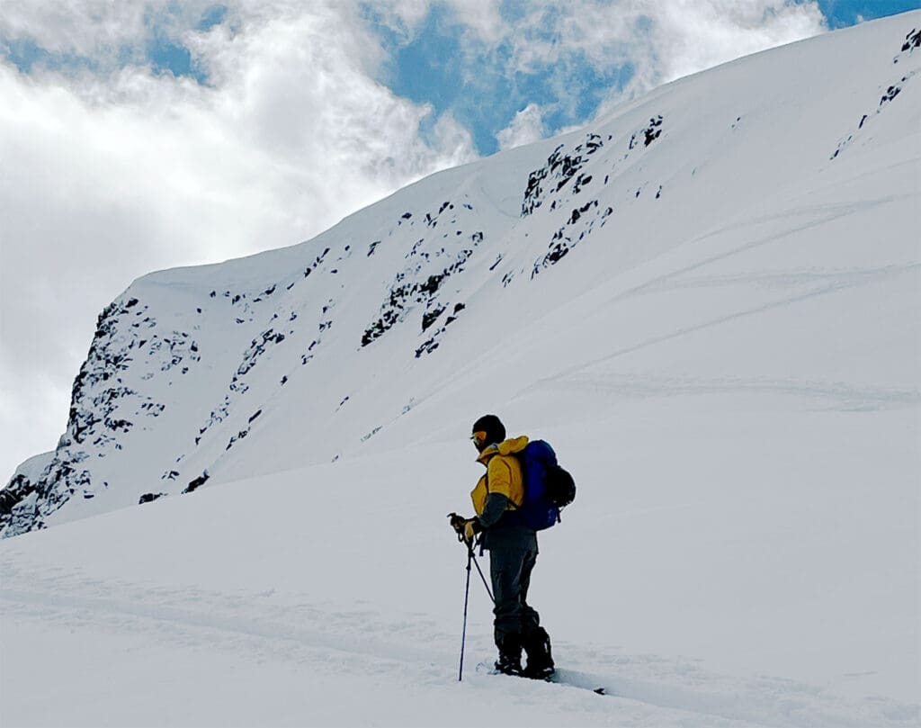 a splitboarder climbs a mountain while testing gear