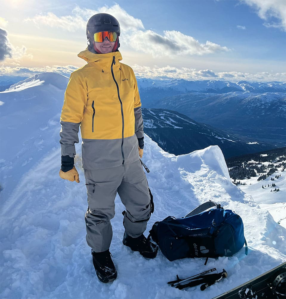 a backcountry snowboarder stands high on a mountain while transitioning