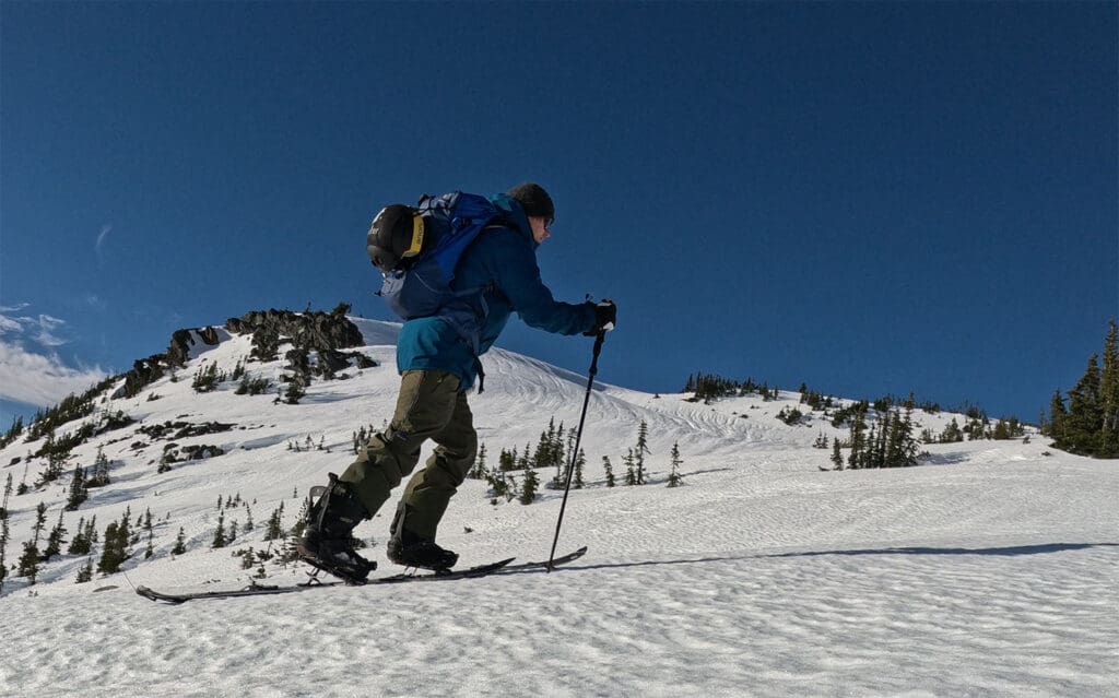 a splitboarder skins uphill while testing splitboarding boots