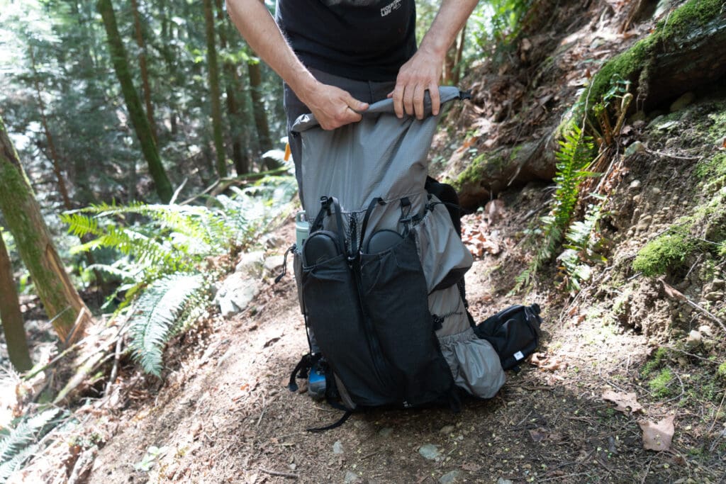rolling down the roll top on a backpack in the forest