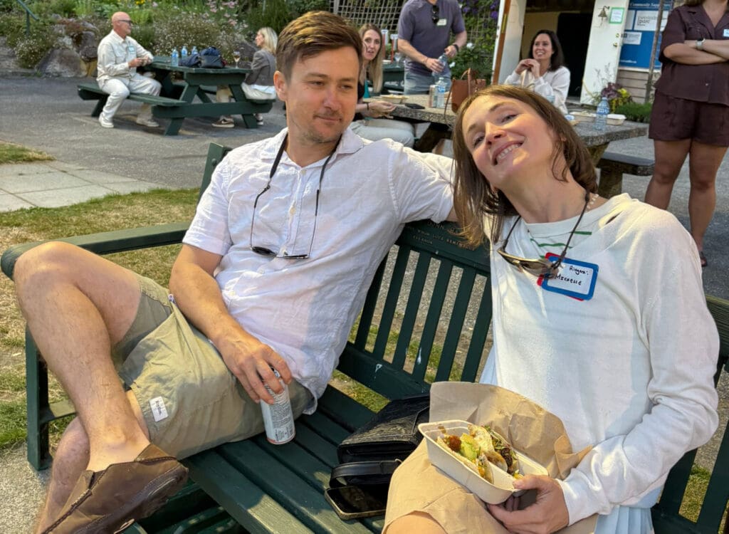 a couple sitting on the bench at a lawn bowling club dressed up in white