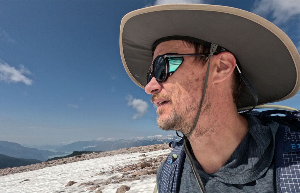 a profile view of a mountaineer hiking on a snow field with the vuarnet glacier glasses