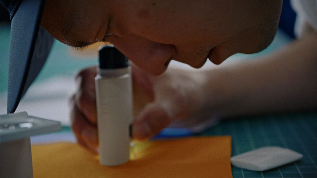 a closeup image arcteryx materials designer andrew yip inspecting fabric on the design table