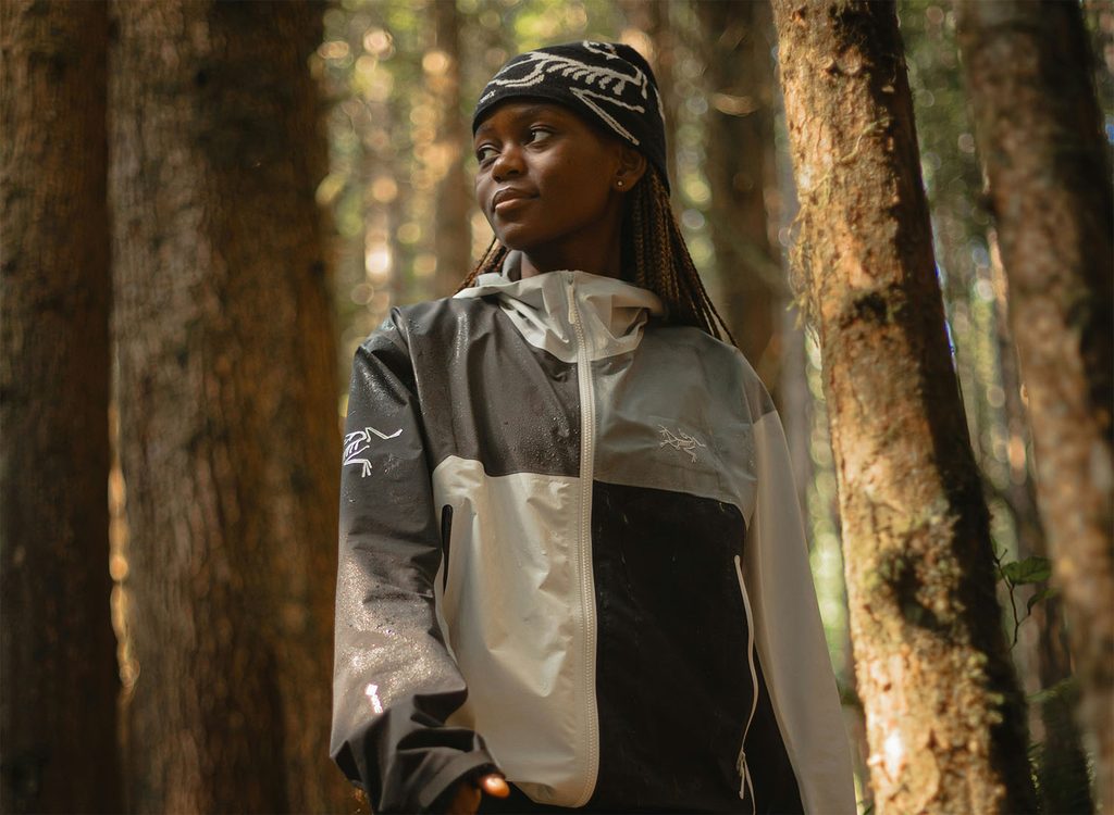 a woman poses in the forest with arcteryx gear
