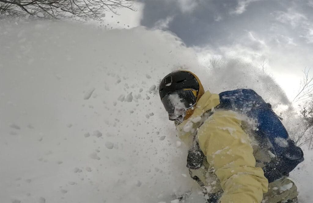 a snowboarder emerges from a cloud of powder while testing the rocky talkie mountain radio