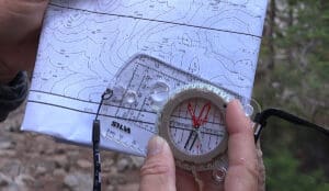 a close up photo of someone using a compass lined up on a topographic map