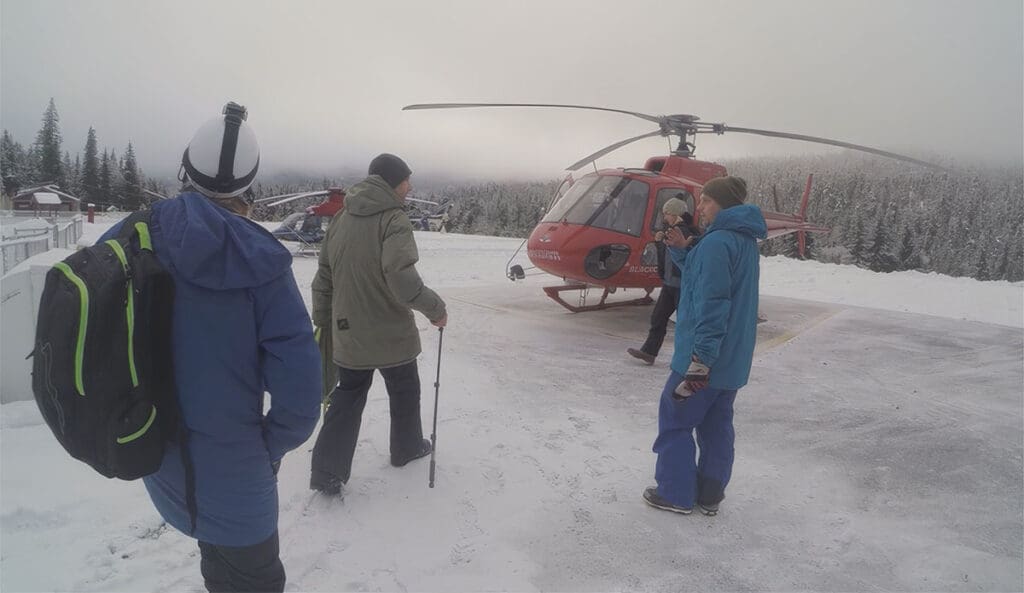 a group of snowboarders head to a helicopter to go heliboarding in whistler