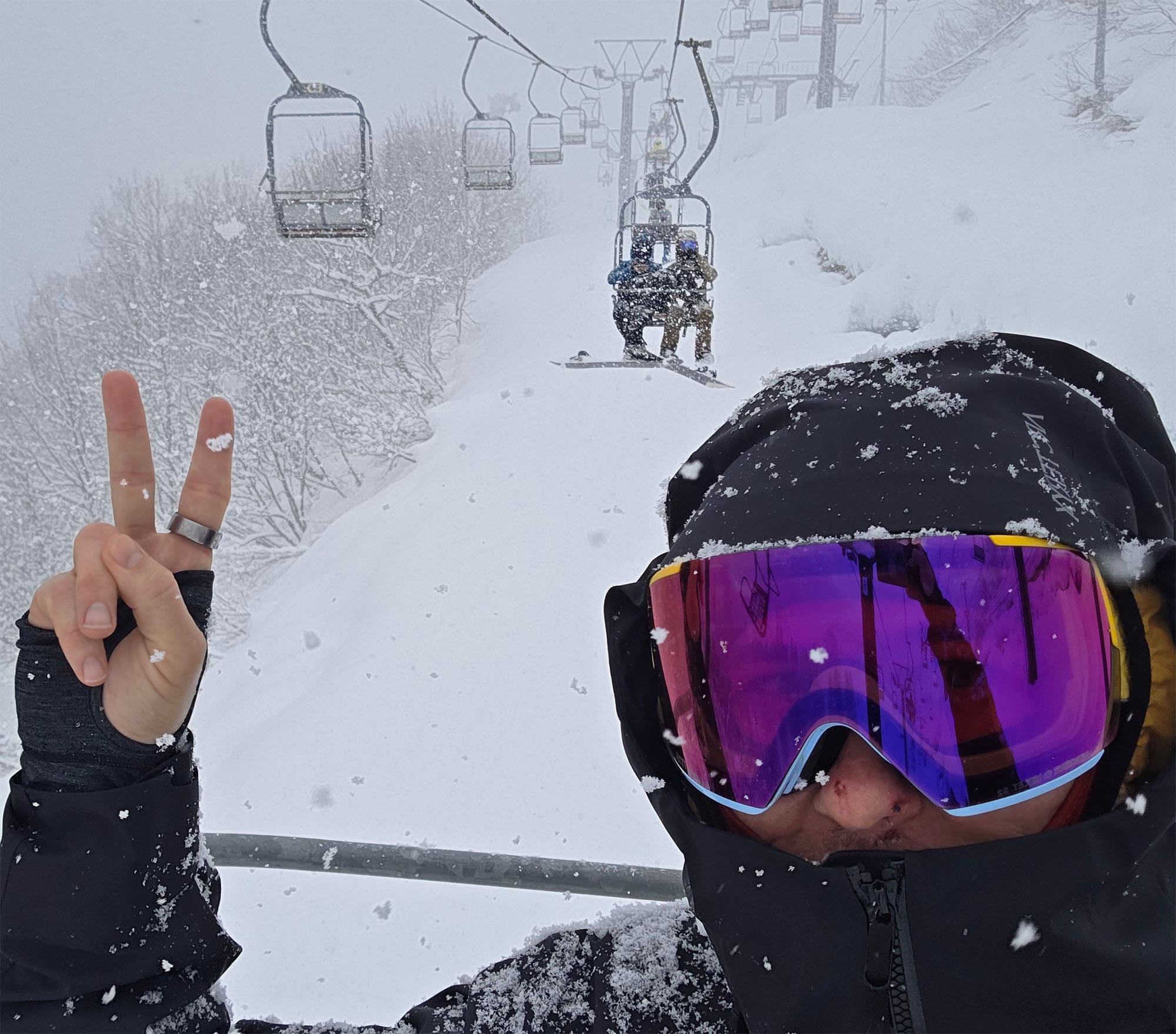 a snowboarder rides deep powder in Japan during a storm wearing Anon M5 goggles