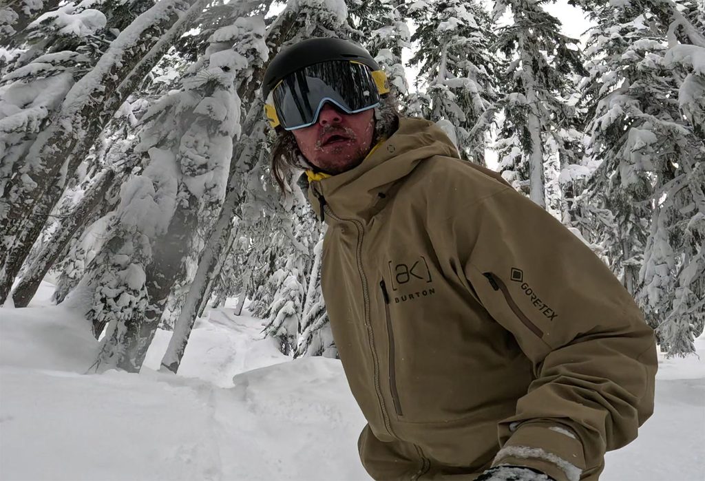 a snowboarder riding through the trees with a selfie angle