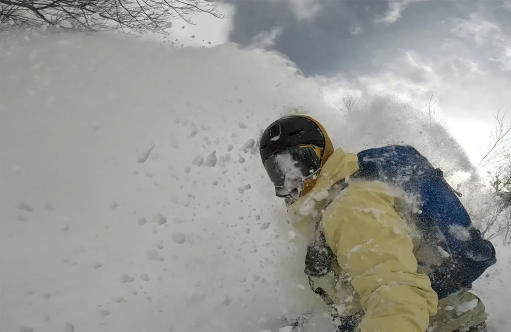 a snowboarder emerges from a cloud of powder while riding in Japan
