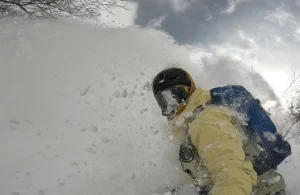a snowboarder emerges from a cloud of powder in Japan