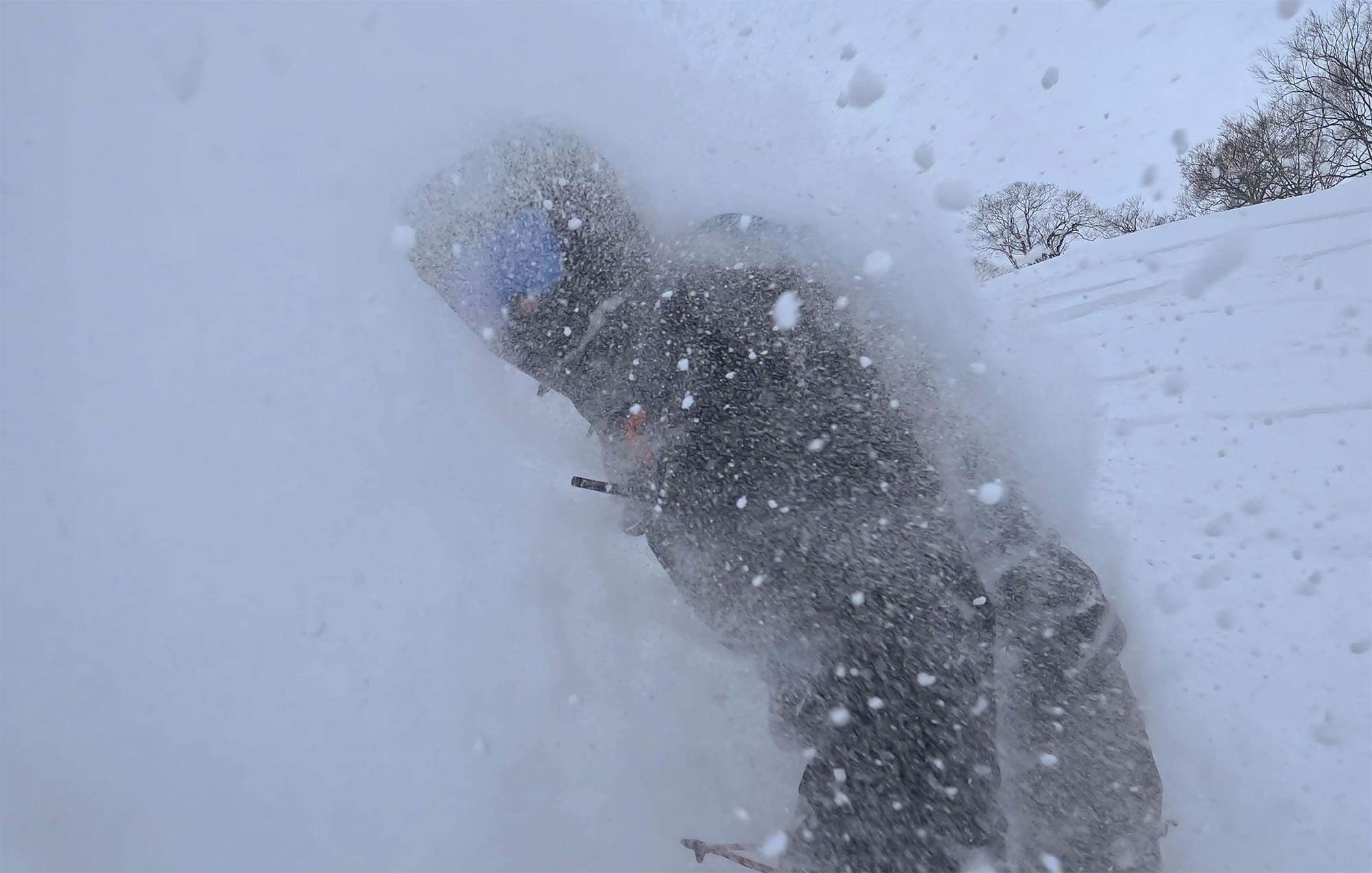 a snowboarder rides through deep powder wearing snow goggles