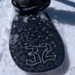 a closeup view of the thirtytwo crucible snowboard back end on snow