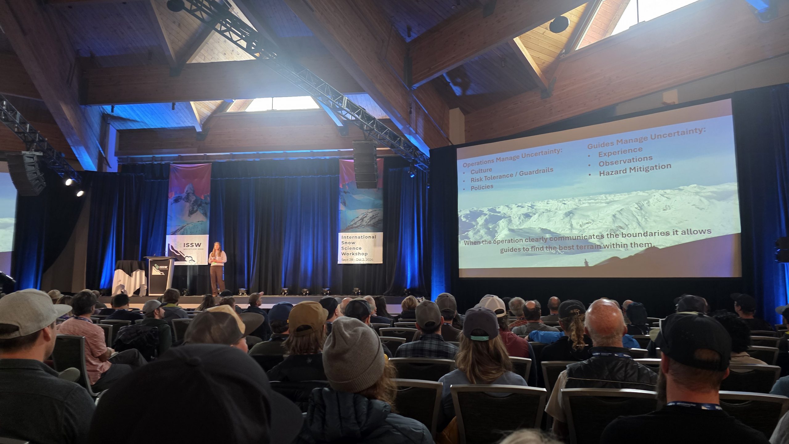a presenter speaks onstage at the international snow science workshop at the whistler conference center