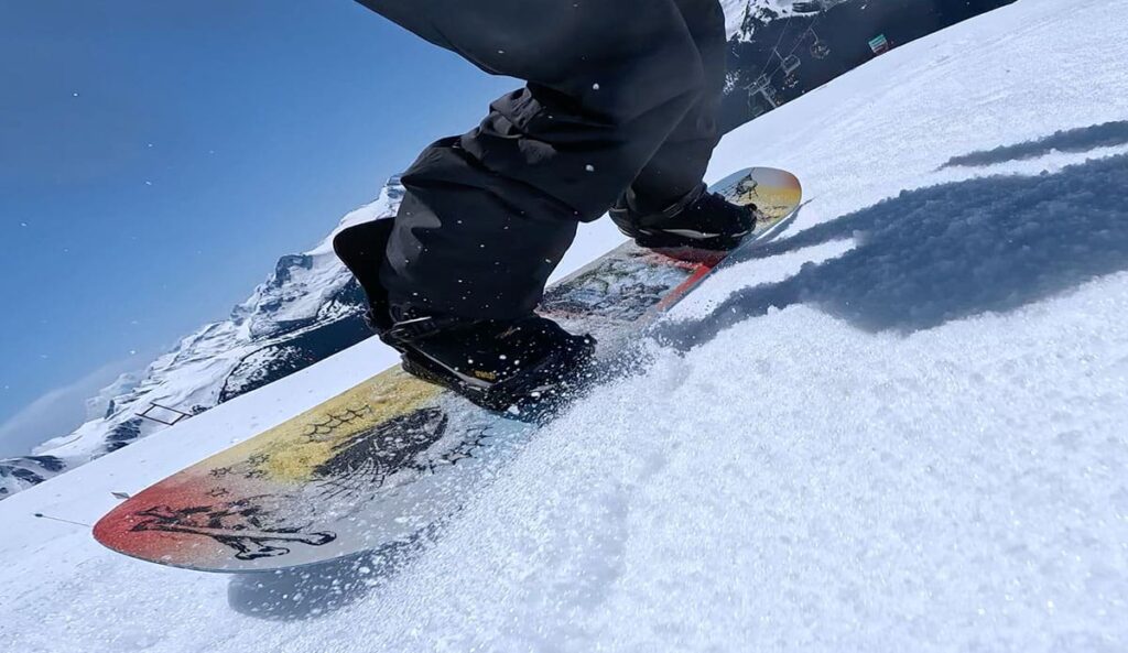 a low angle view of a snowboarder carving in the spring slush