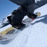 a low angle view of a snowboarder carving in the spring slush