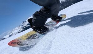 a low angle view of a snowboarder carving in the spring slush